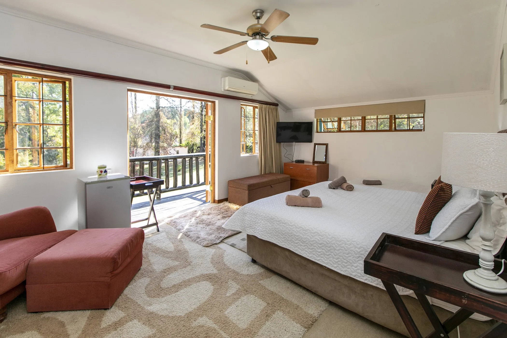 Cozy bedroom with a large bed ceiling fan and a view of a balcony