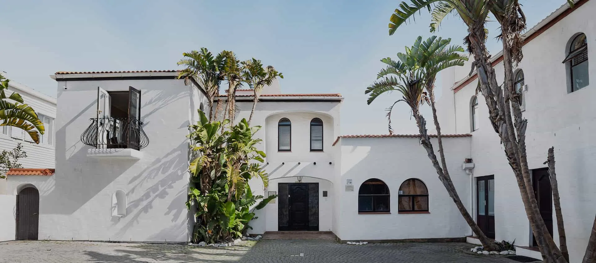 White Spanishstyle building with arched windows and palm trees in courtyard