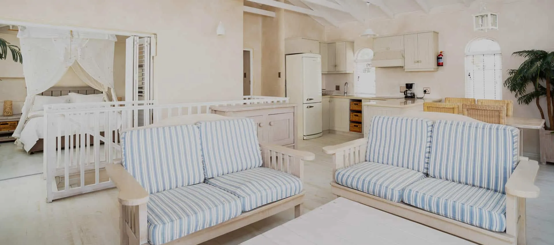 Open living area with striped sofas kitchen and crib in a bright room