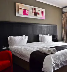 Modern bedroom with large bed artwork and red chair