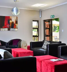 Modern living room with black sofas red ottomans and large windows