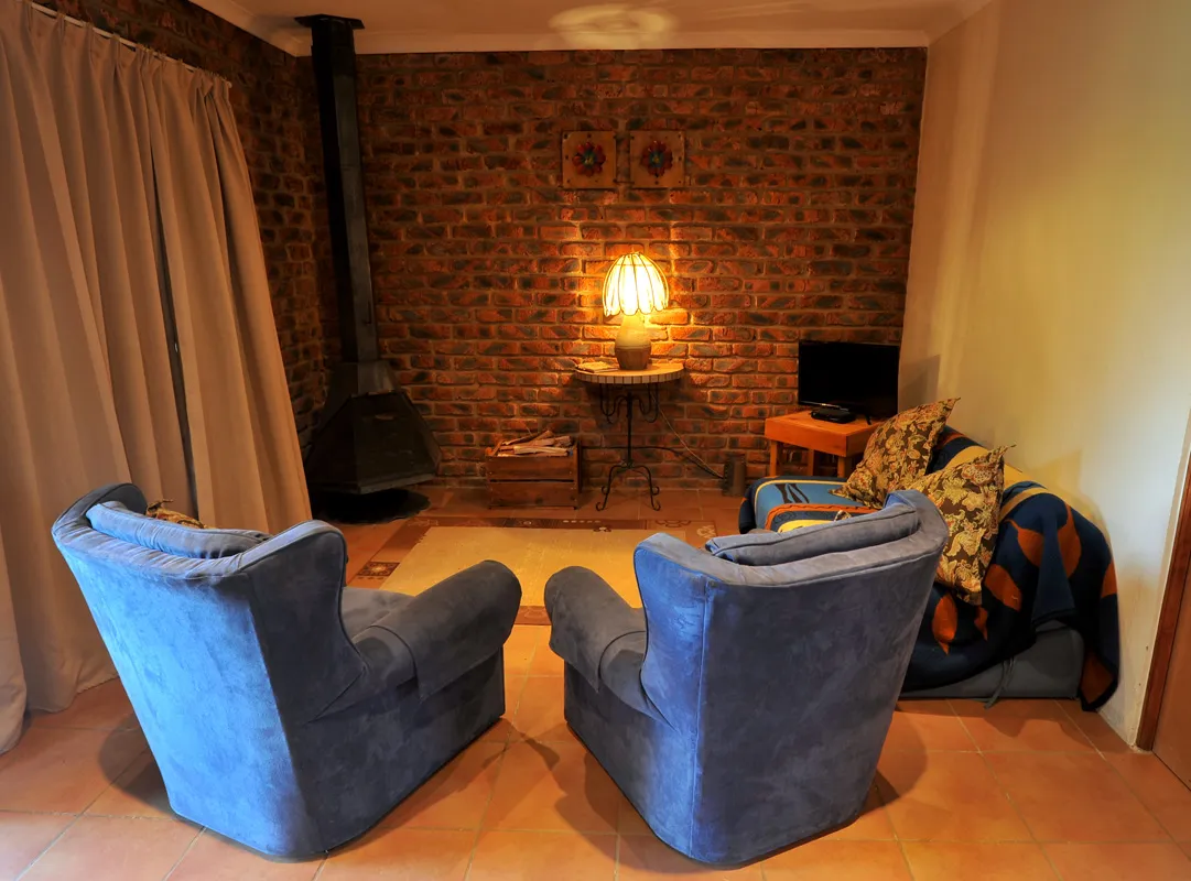 Two blue armchairs facing a cozy brick fireplace in a living room