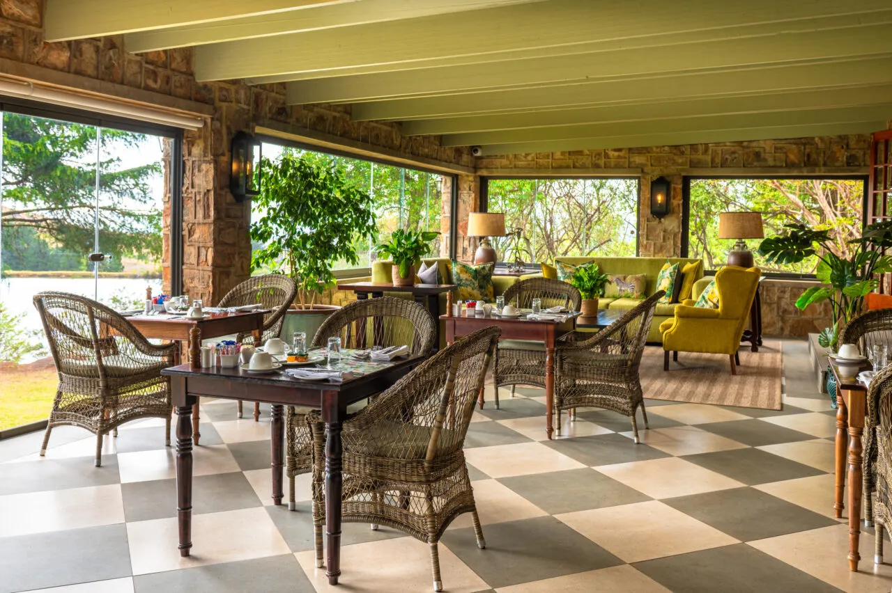 Cozy outdoor dining area with wicker furniture and large windows overlooking greenery