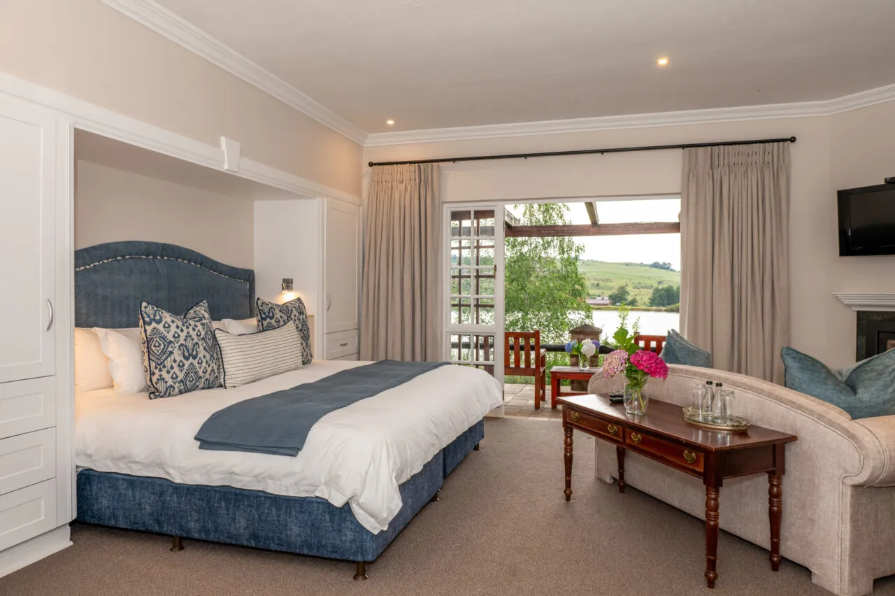 Luxurious bedroom with large bed view of garden and fireplace