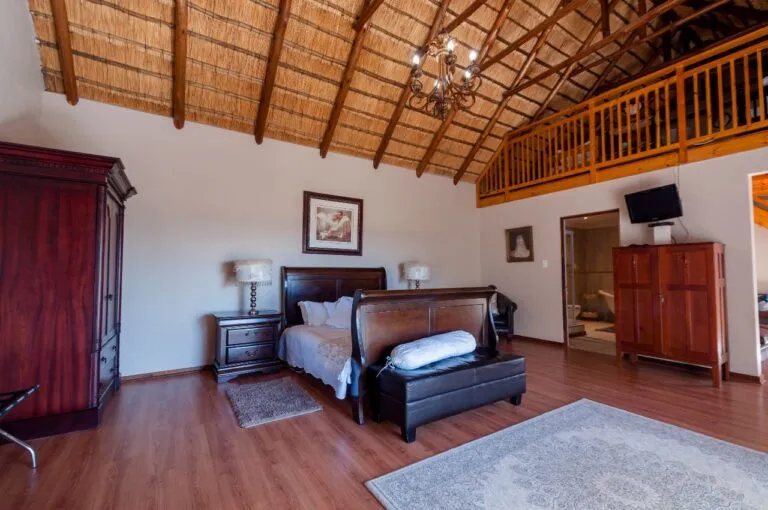 Wooden bedroom with high thatched ceiling large bed and wooden furniture