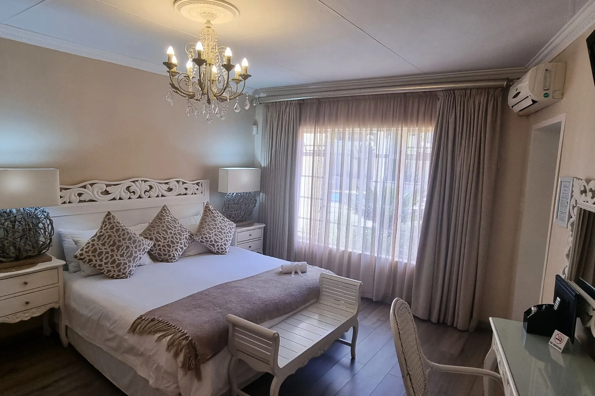 Elegant bedroom with large bed chandelier and large window with curtains