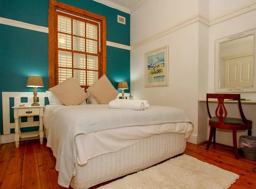 Cozy bedroom with a bed nightstand lamp and mirror on wooden floor