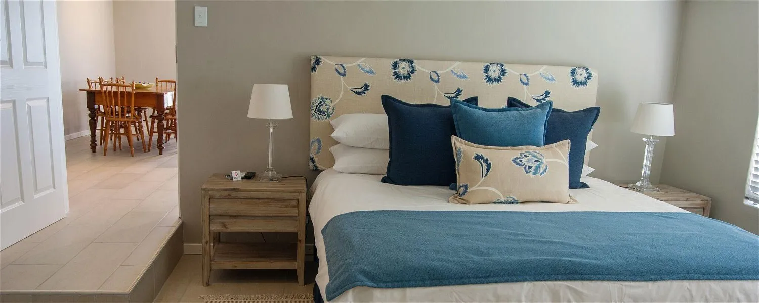 A neatly made bed in a bedroom with floral headboard and side tables