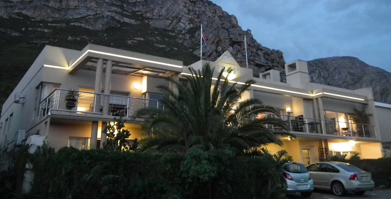 Modern building with balconies and palm trees in front mountains in the background
