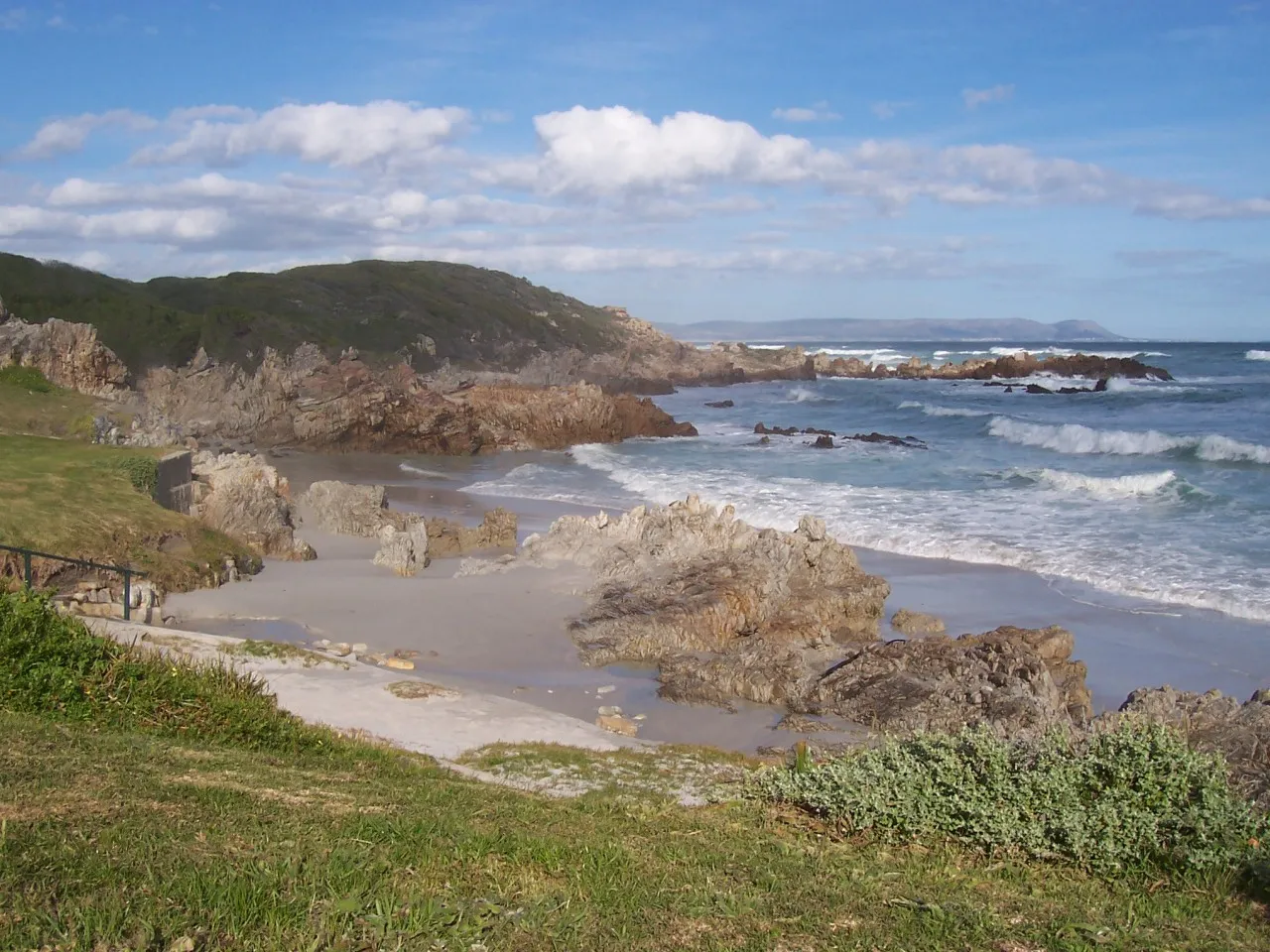Rocky coastline with waves crashing against rocks under a clear blue sky