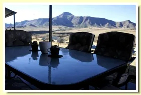 Outdoor table with chairs overlooking mountainous landscape under a clear sky