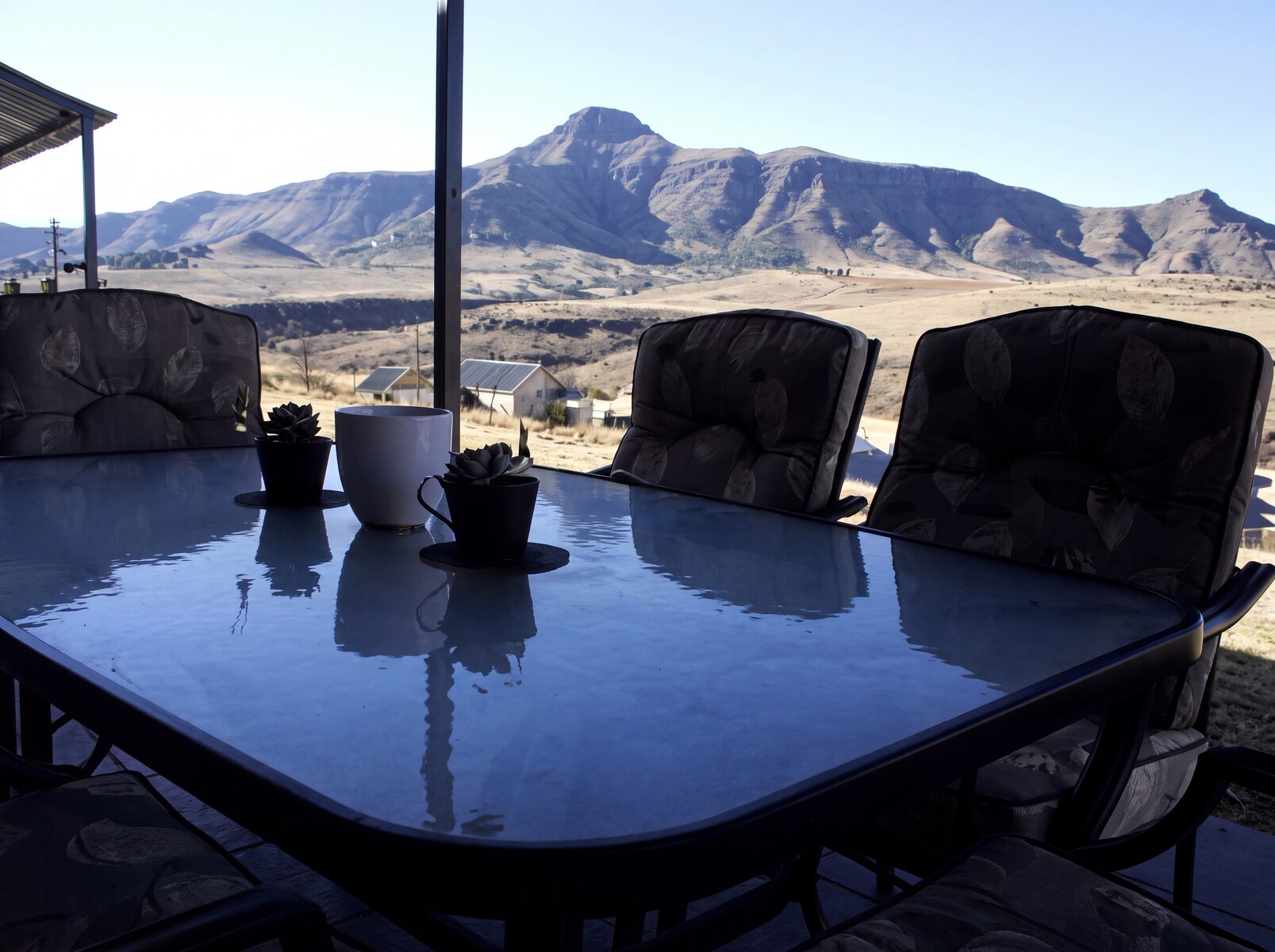 Outdoor table with chairs overlooking mountainous landscape under a clear sky