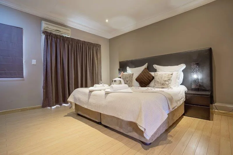 Modern bedroom with large bed wooden floor and window with curtains