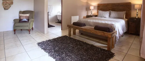 Bedroom with wooden bed bench armchair and attached bathroom