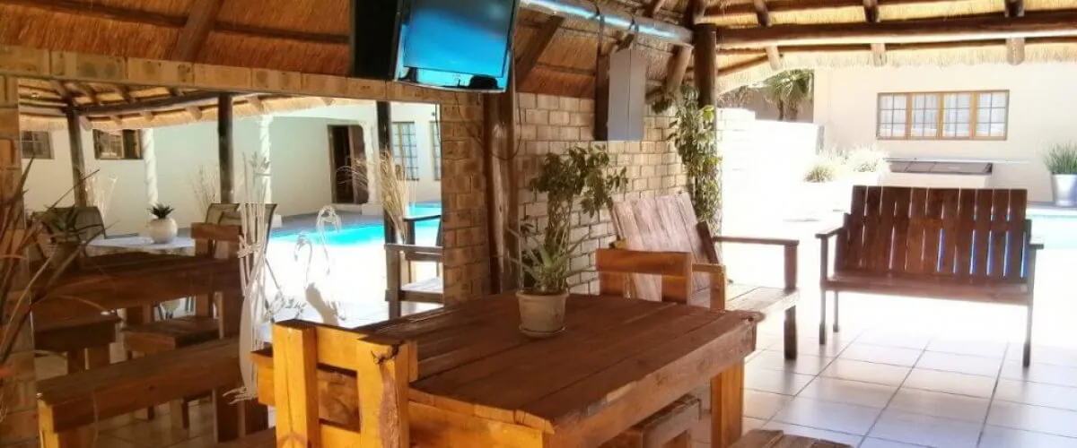 Wooden patio furniture and a TV overlooking a swimming pool area