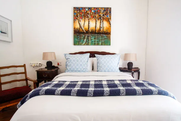 Cozy bedroom with a neatly made bed two nightstands and a colorful painting