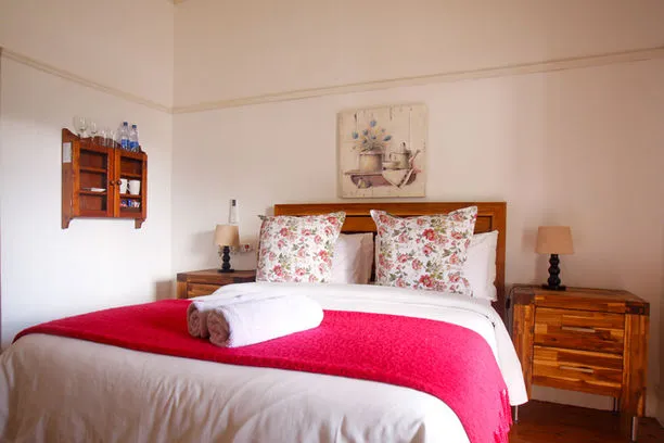 Cozy bedroom with a bed floral pillows red blanket and wooden furniture