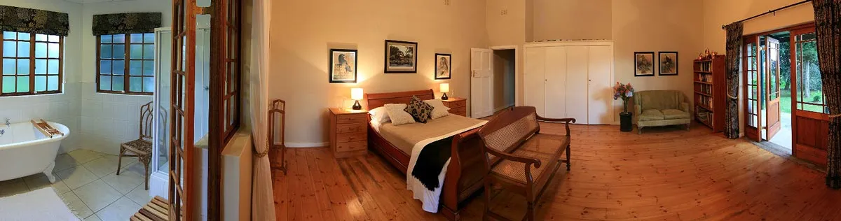 Bedroom with wooden floors bed sofa and adjacent bathroom with bathtub