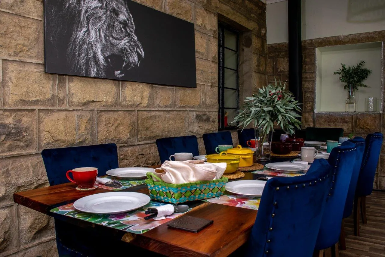 Dining table with blue chairs floral centerpiece and wall art in a rustic room
