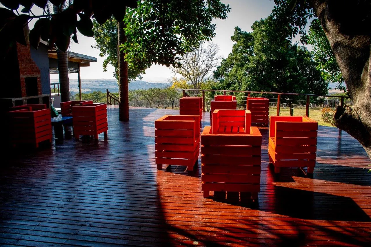 Wooden deck with red chairs and tree shade overlooking a scenic landscape