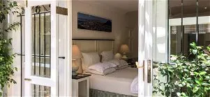 Open door leading to a neatly made bed in a bright bedroom