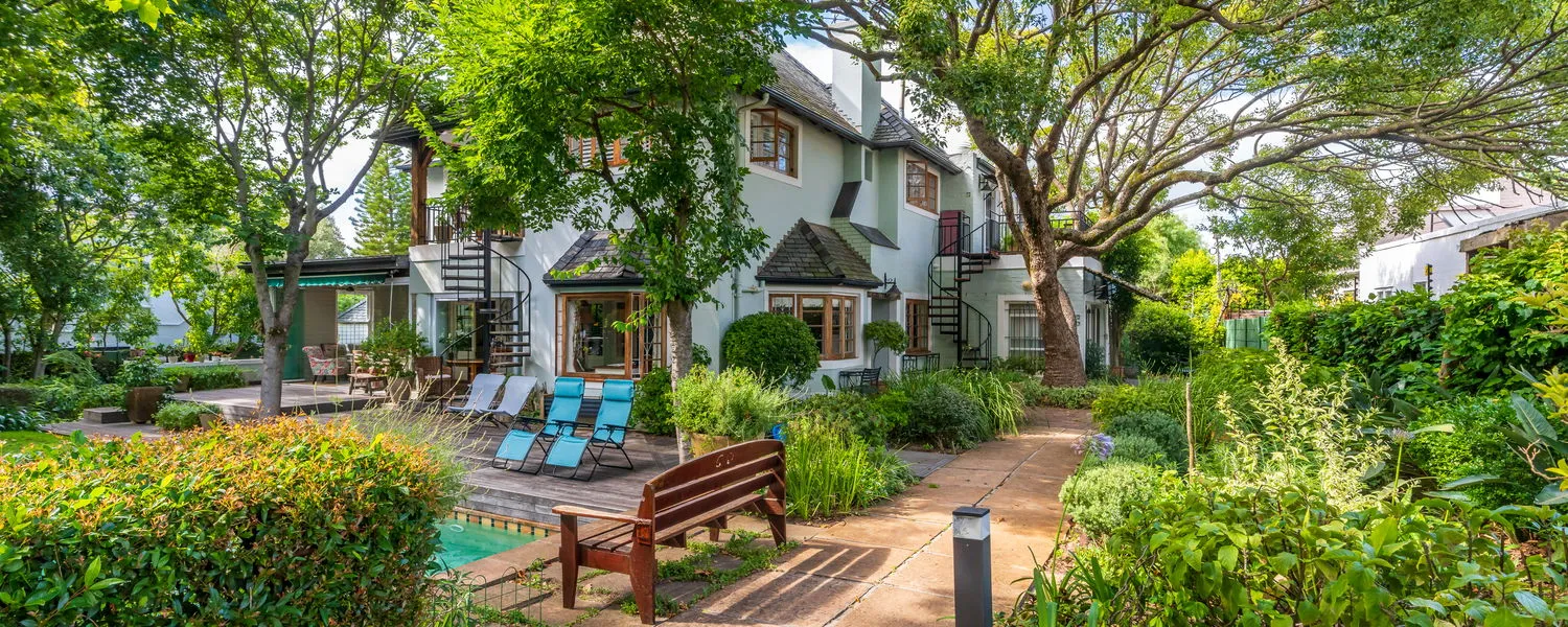 Garden with a bench pool and a house surrounded by lush greenery