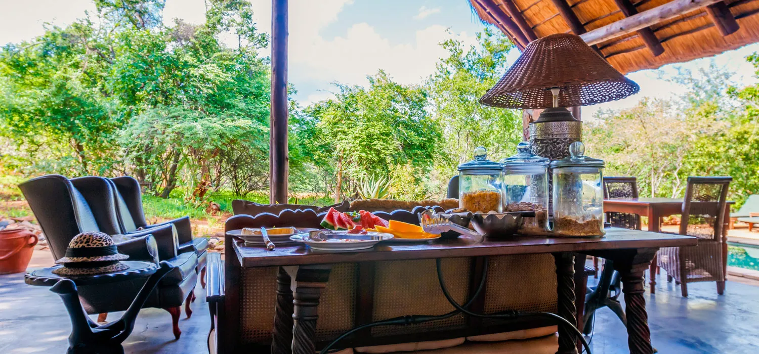 Outdoor seating area with a table set for breakfast in a lush garden