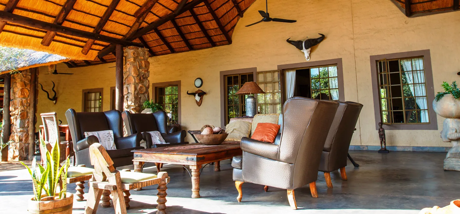 Cozy outdoor lounge area with rustic furniture and decor under a wooden roof