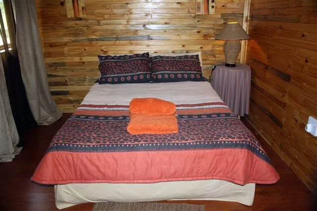 Wooden cabin bedroom with a neatly made bed and bedside lamp