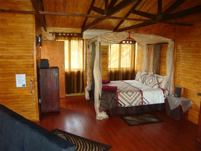 Wooden cabin bedroom with a fourposter bed and hardwood floor