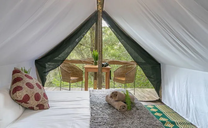 Cozy tent interior with bed towels and view of outdoor seating area