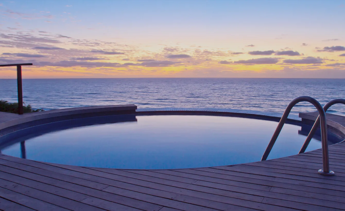 Small pool with ocean view at sunset wooden deck and metal railing