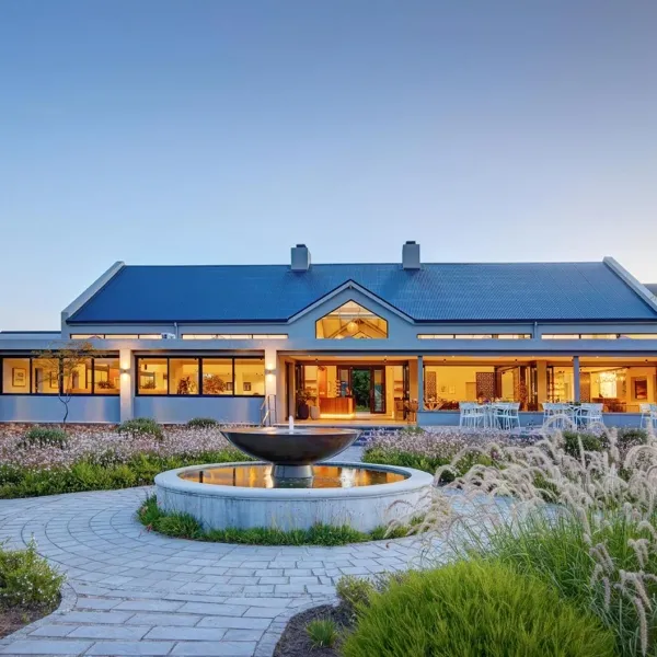 Modern house with large windows and a circular fountain in the garden at dusk