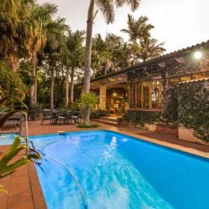 Tropical garden with pool and house in the background at dusk