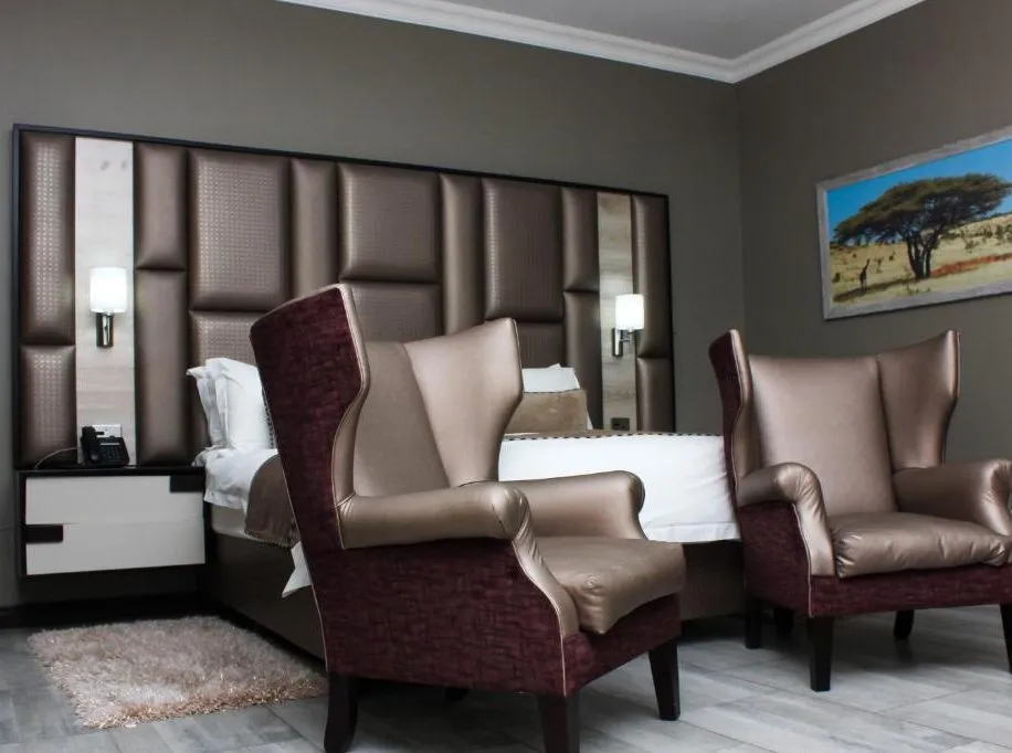 Modern hotel room with two armchairs bed and wall art