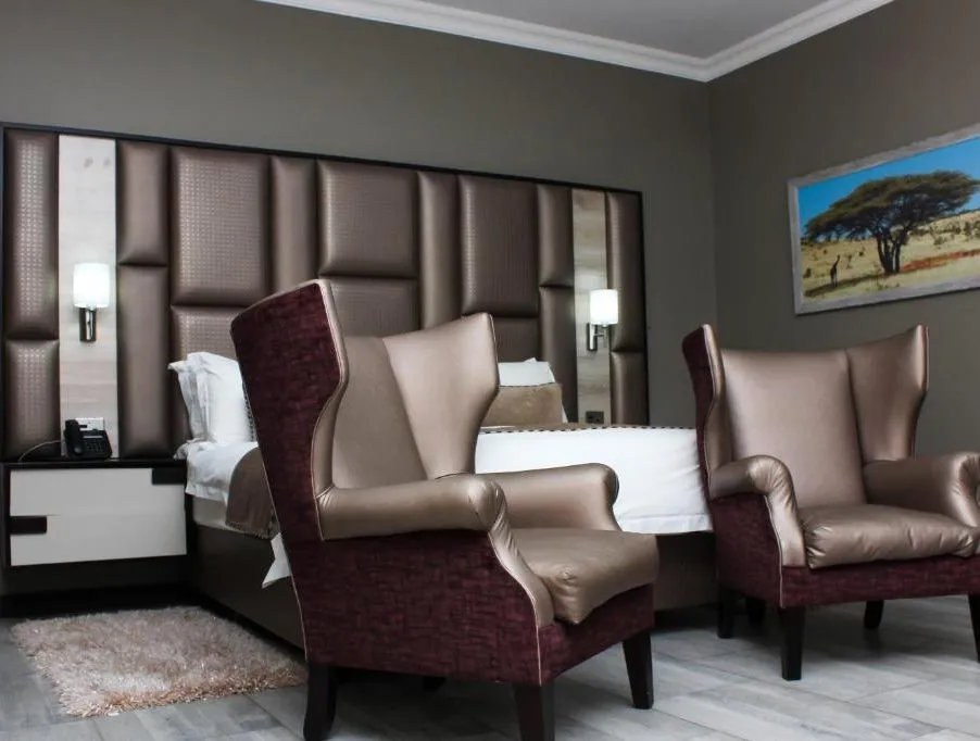 Modern hotel room with large bed two armchairs and African landscape artwork