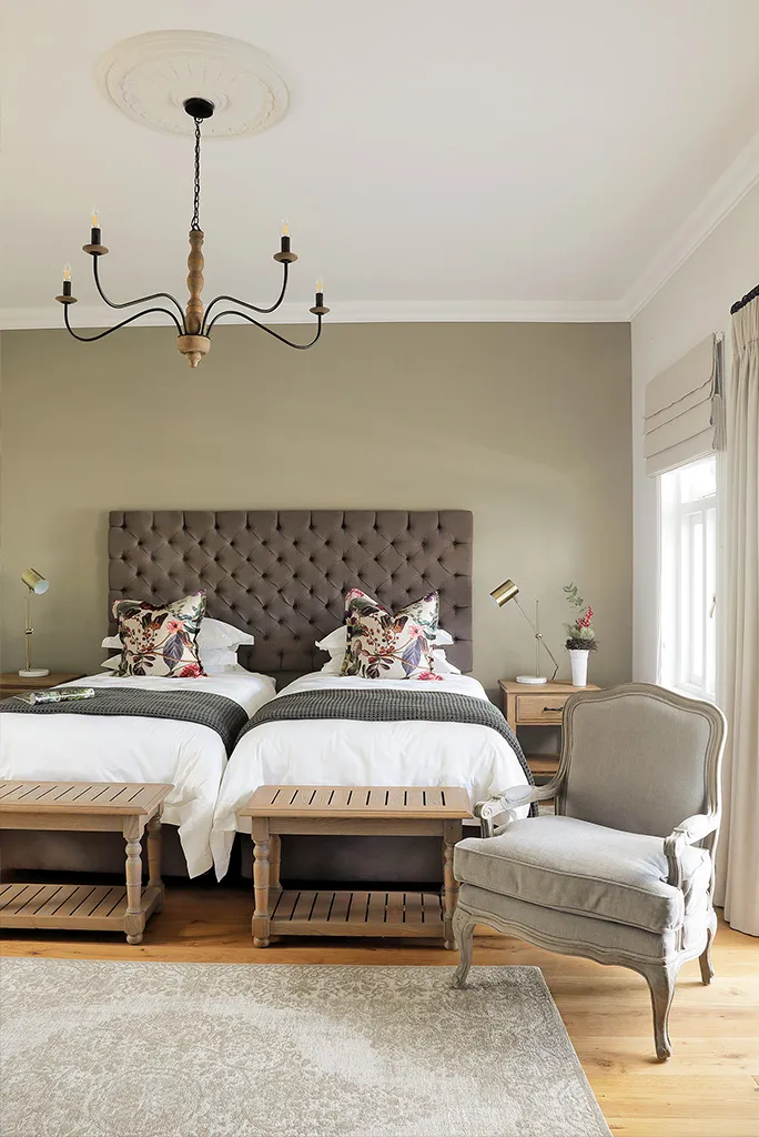 Bedroom with two single beds armchair and wooden furniture on a wooden floor