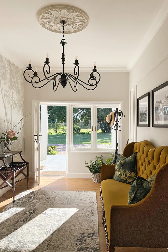 Sunlit hallway with chandelier yellow sofa and open door to garden