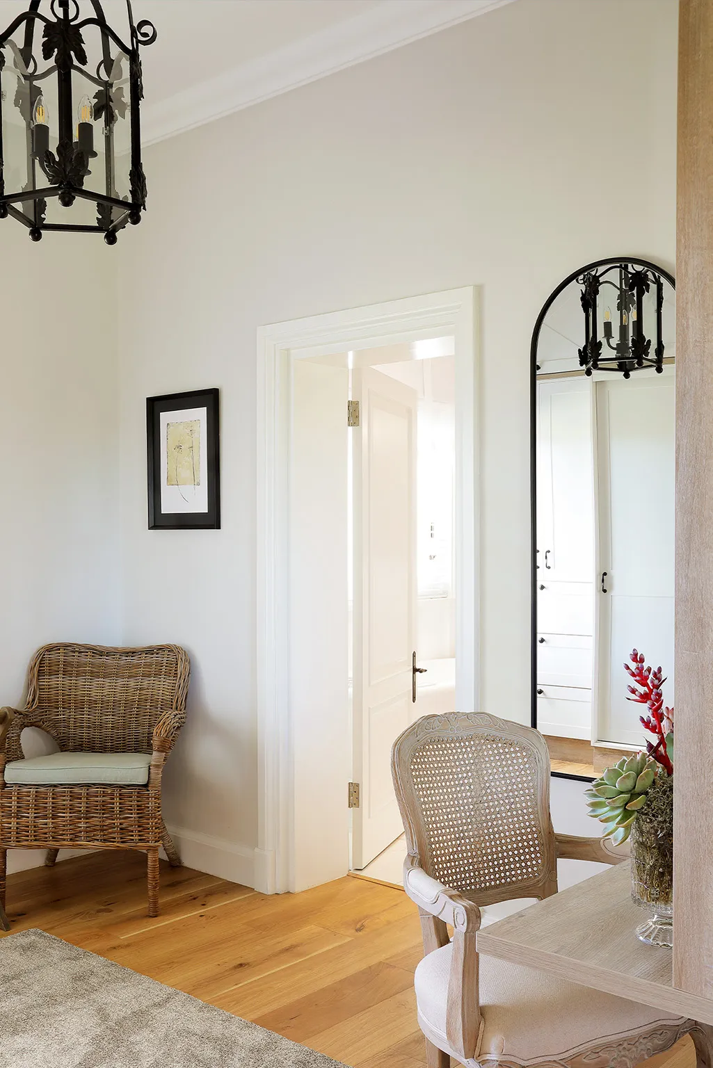 Wicker chair wooden floor open door to bathroom mirror and table with plant