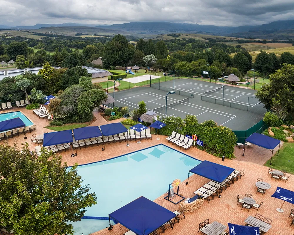 Resort with swimming pool tennis courts and lounge chairs in a scenic landscape