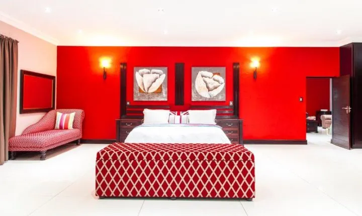 Red bedroom with large bed patterned bench and modern decor