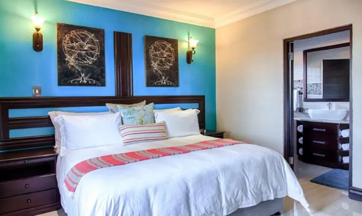 Bedroom with blue accent wall large bed and adjacent bathroom