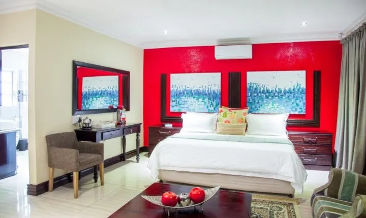 Modern bedroom with red accent wall white bed and wooden furniture