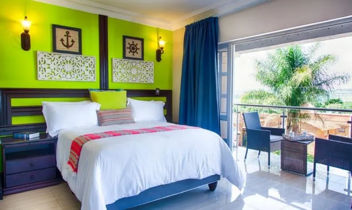 Bright bedroom with green walls large bed and balcony view of palm trees