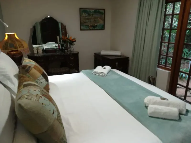 Neatly made bed with pillows towels and a window with curtains