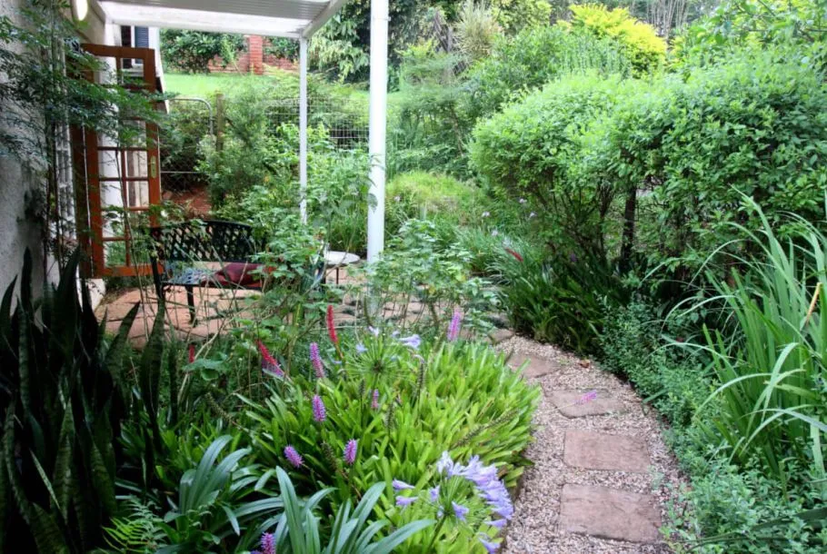 Garden path with flowers leading to a patio with a bench and house