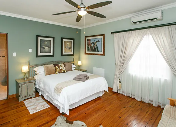 Bedroom with a large bed ceiling fan and large windows with curtains