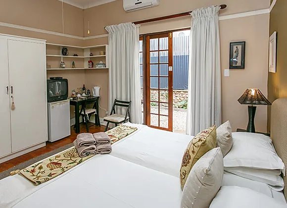 Cozy bedroom with two single beds white curtains and a small desk