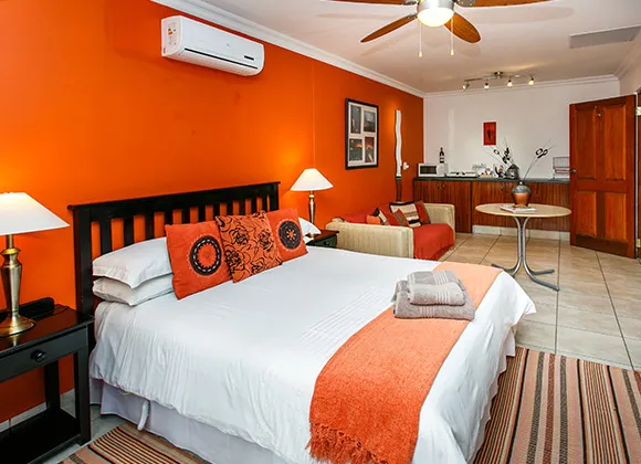 Bright orange bedroom with large bed sofa and wooden furniture