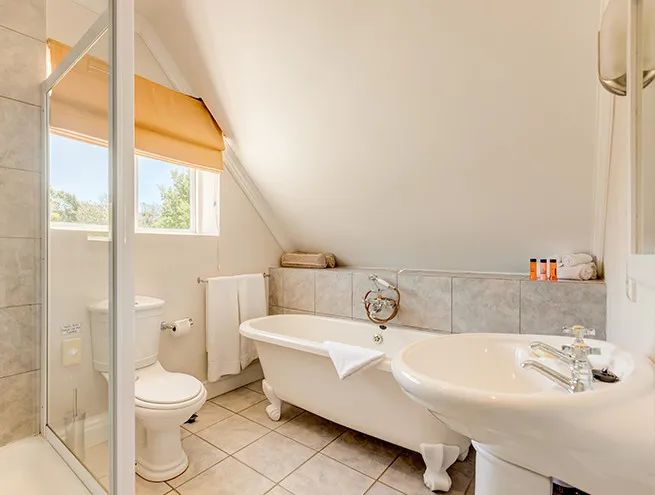 White bathroom with clawfoot tub toilet sink and large window